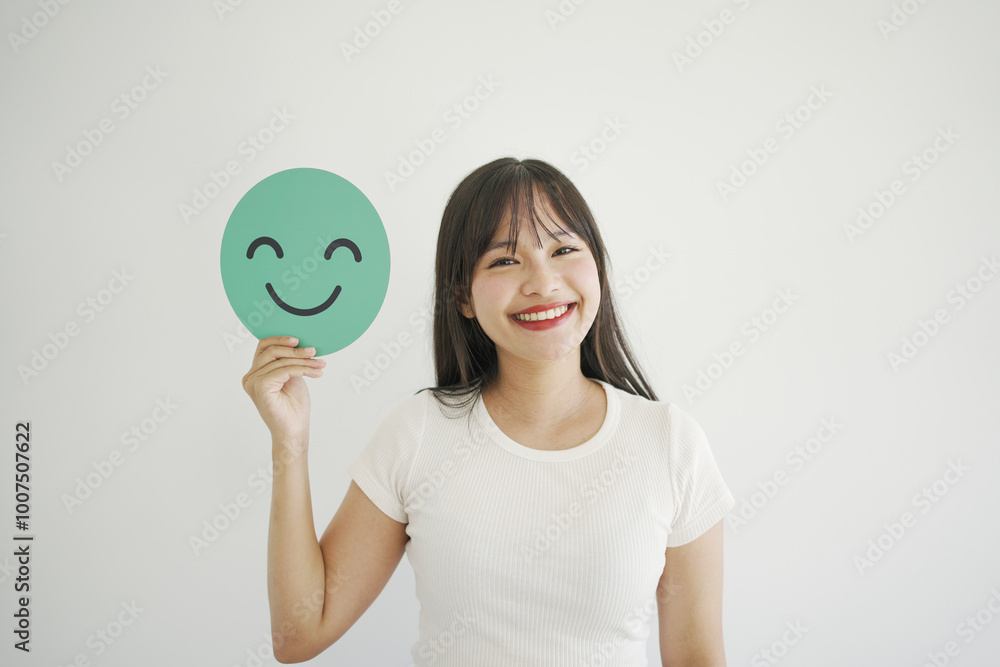 Happy young Asian woman holding smile emoji face, positive mental health, world mental health day concept
Happy young Asian woman holding smile emoji face, positive mental health, world mental health day concept