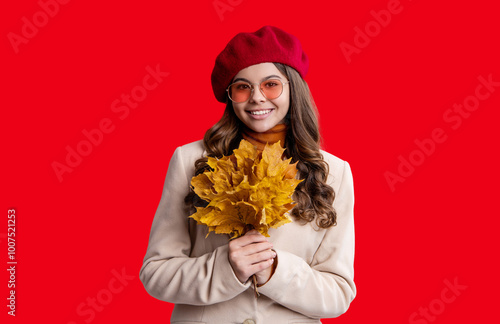 Autumn girl hold fallen leaves. Fall and autumn. Autumnal season. Fall fashion. Happy young girl playfully hold yellow maple leaves. Teen girl with fallen leaves isolated on red. Autumn maple foliage photo