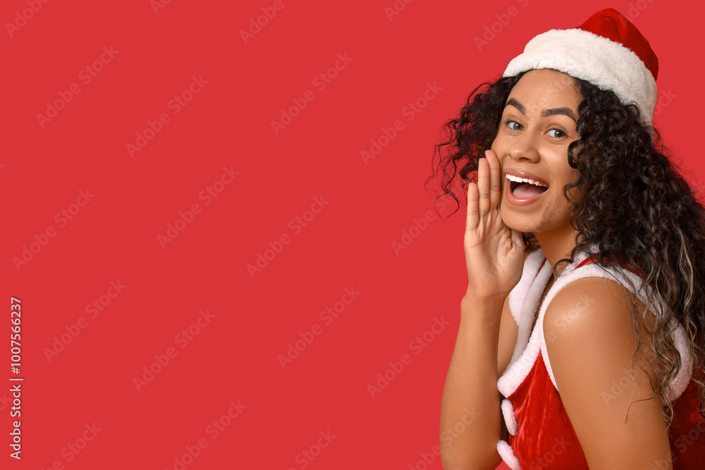 Beautiful young happy African-American woman in sexy Santa costume on red background Beautiful young happy African-American woman in sexy Santa costume on red background