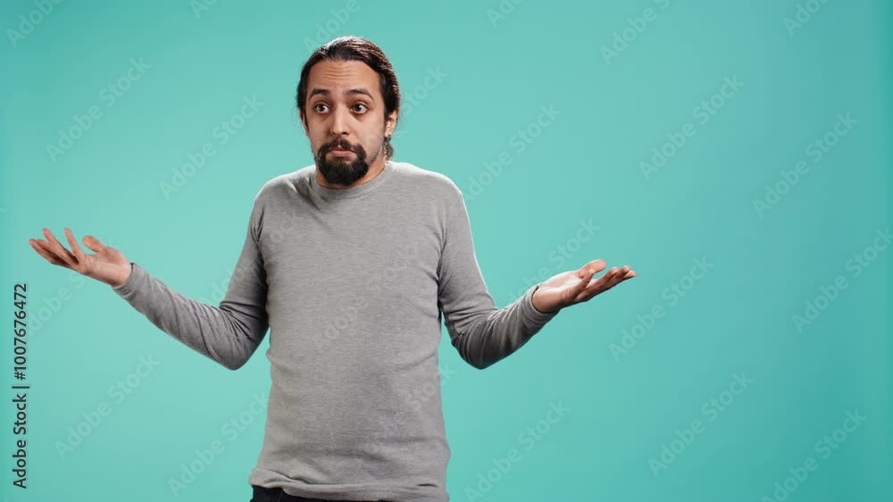Man shrugging shoulders, unable to provide answer, having detached apathy facial expression. Apathetic person doing hand gesturing showing lack of knowledge, studio background, camera B