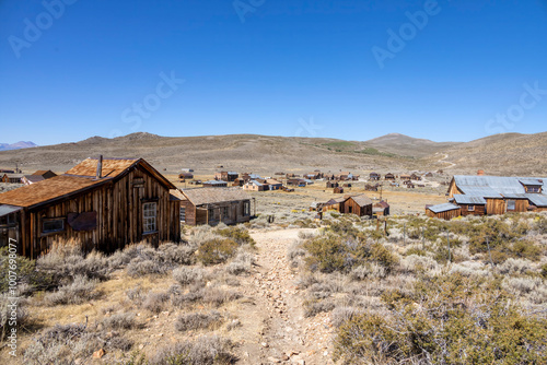 Bodie State Historical Park in California showcases a well-preserved ghost town from the Gold Rush era. Wooden structures stand frozen in time amidst the rugged high desert landscape. photo