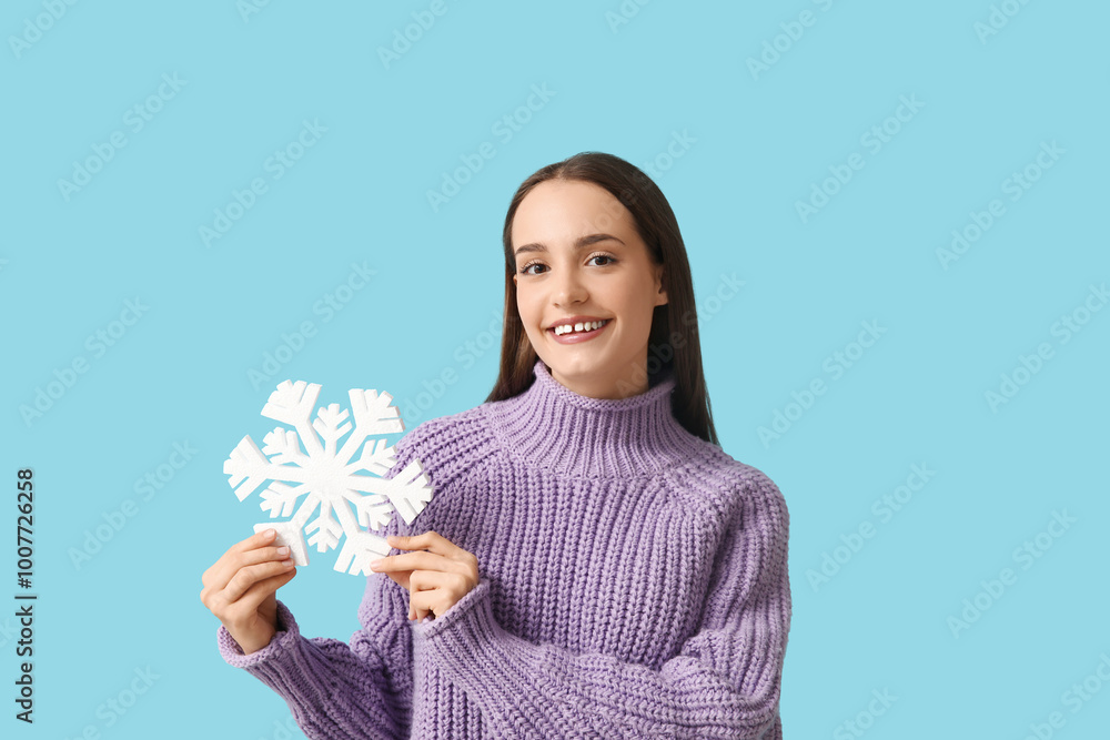 Young woman in knitted sweater with snowflake on blue background Young woman in knitted sweater with snowflake on blue background