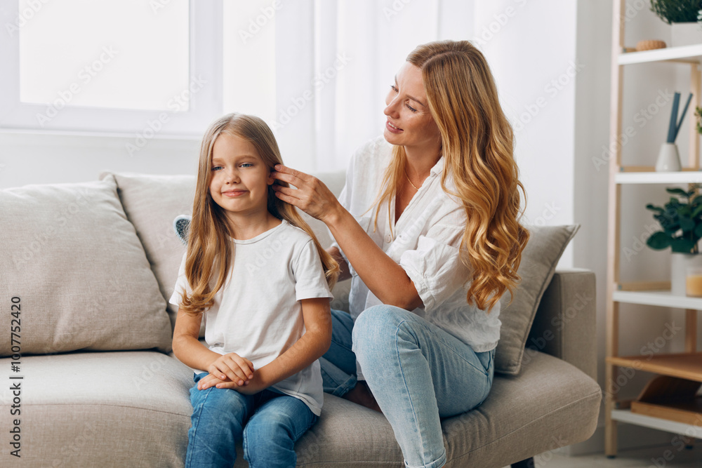 Mother and daughter sharing a cozy moment on the couch, reading a book together in a bright living room Mother and daughter sharing a cozy moment on the couch, reading a book together in a bright living room