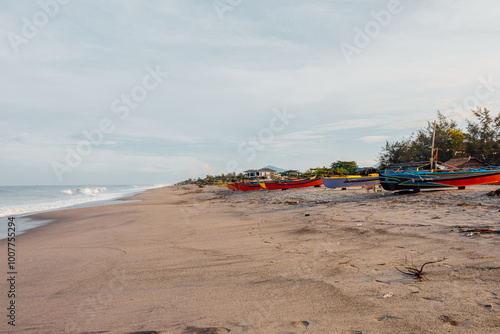 Beautiful fine white sand beach with fishing boats at the shore. photo