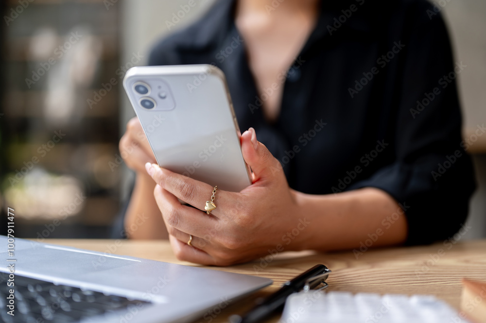 A close-up of a businesswoman's hand holding her smartphone, using her smartphone at the desk. A close-up of a businesswoman's hand holding her smartphone, using her smartphone at the desk.