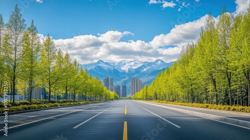 Scenic view of a vast road flanked by lush trees, leading towards majestic mountains under a bright blue sky.