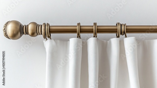 Close-up of a gold curtain rod with white curtains against a white wall.