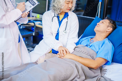 A middle-aged man lies bedridden on hospital bed, closely monitored by an old Asian woman doctor and young nurse. They assess his symptoms, including heart and lung conditions, offer advice.