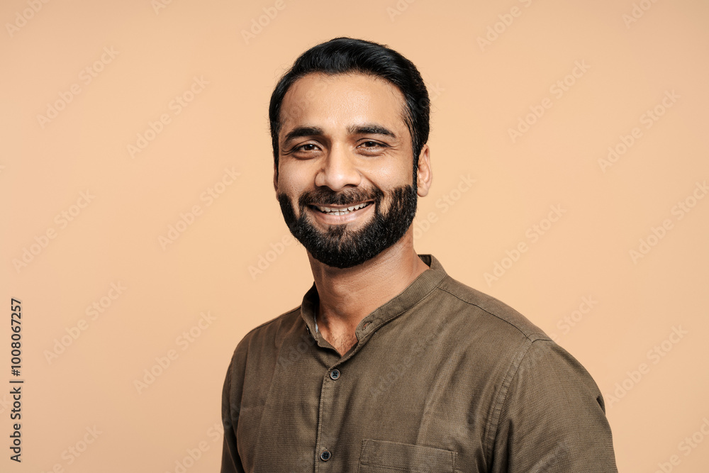 Fototapeta premium Portrait of positive, handsome indian man smiling and posing isolated on beige background