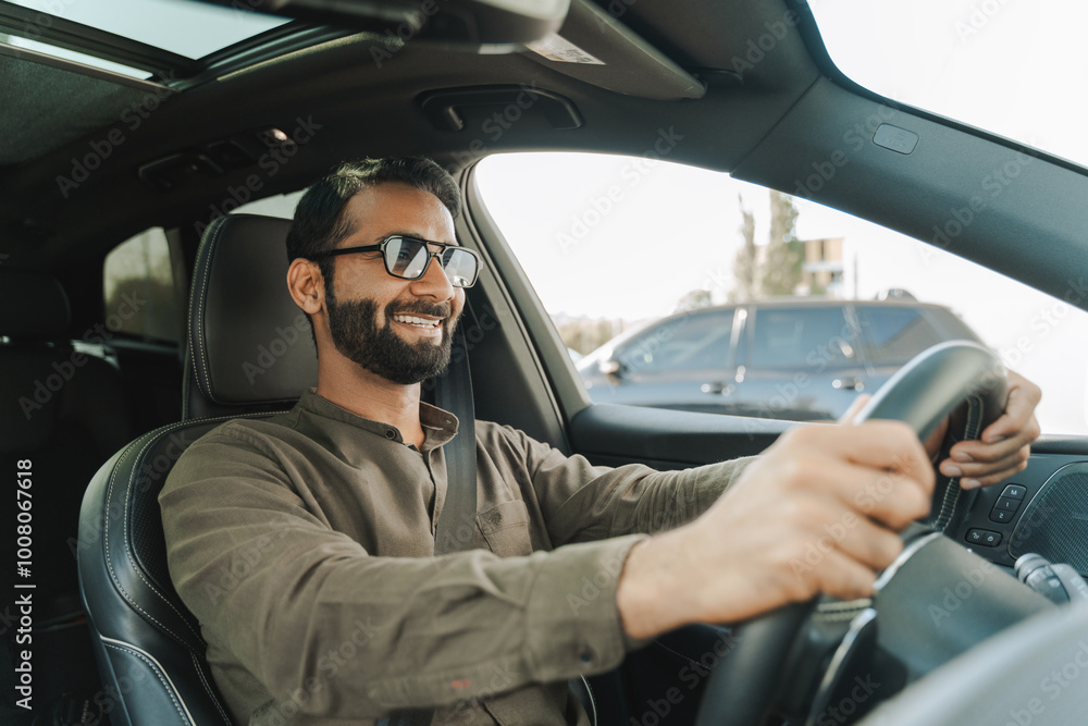 Handsome middle aged Indian man smiling while driving his car Handsome middle aged Indian man smiling while driving his car
