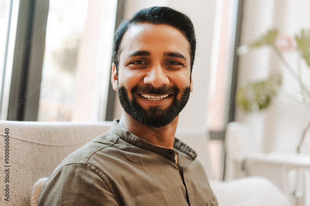 Portrait of handsome smiling Indian businessman, employee sitting in modern office Portrait of handsome smiling Indian businessman, employee sitting in modern office