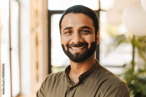 Smiling, middle aged Indian man looking at camera, confident businessman working in modern office