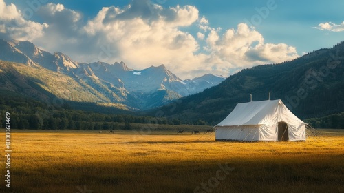 A large white camping tent in a field with mountains, taken during golden hour for a scenic feel. 