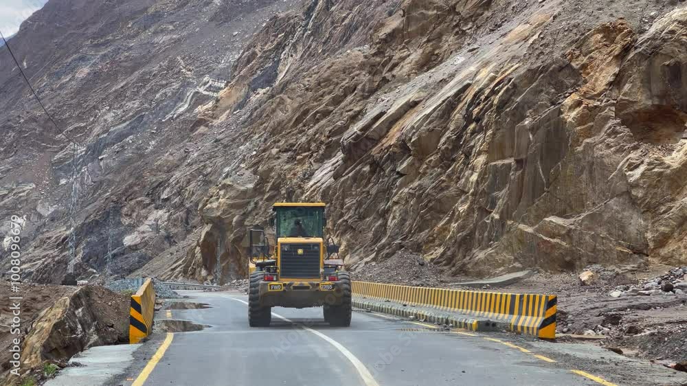 A bulldozer moves along Gilgit Skardu Road, clearing rubble and debris from a recent landslide, showcasing road construction and safety efforts. A bulldozer moves along Gilgit Skardu Road, clearing rubble and debris from a recent landslide, showcasing road construction and safety efforts.