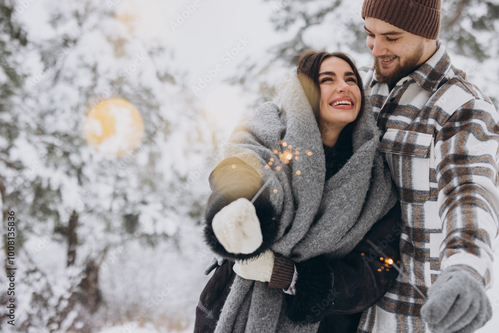 Happy romantic couple in love holding sparklers in snowy winter forest Happy romantic couple in love holding sparklers in snowy winter forest