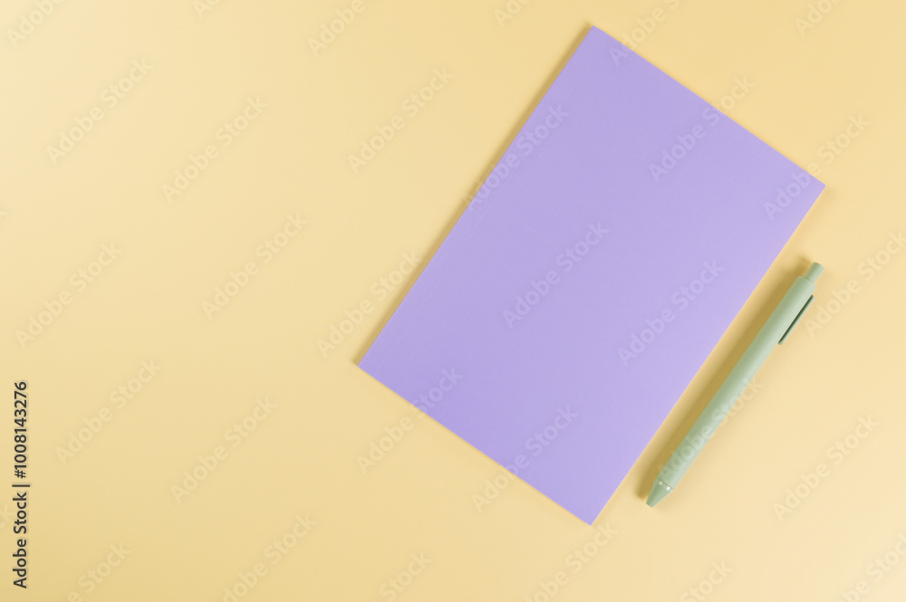 Top view of purple notebook, green pen on yellow background. School, office wallpaper. Flat lay, copy space. Top view of purple notebook, green pen on yellow background. School, office wallpaper. Flat lay, copy space.