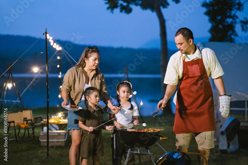 Asian father, mother and daughter are enjoying dinner and camping in nature. Vintage film tone.