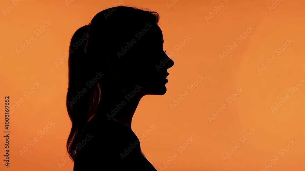 Silhouette of woman in profile against vibrant orange background Silhouette of woman in profile against vibrant orange background