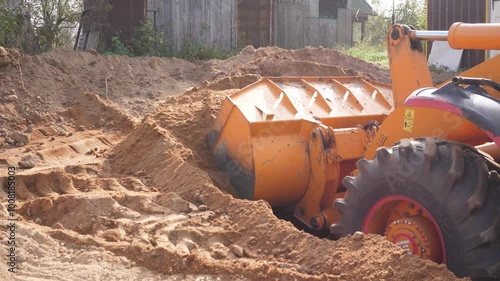 A bulldozer picks up sand at a construction site