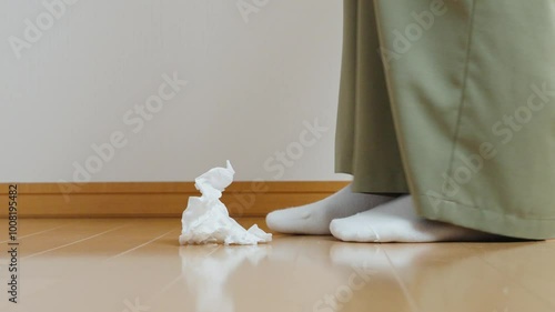 A woman picking up trash in room.  部屋のゴミを拾う女性