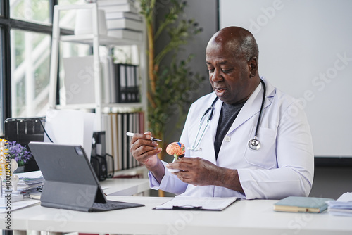 Senior doctor explaining medical concepts through online consultation using brain model and tablet in modern office