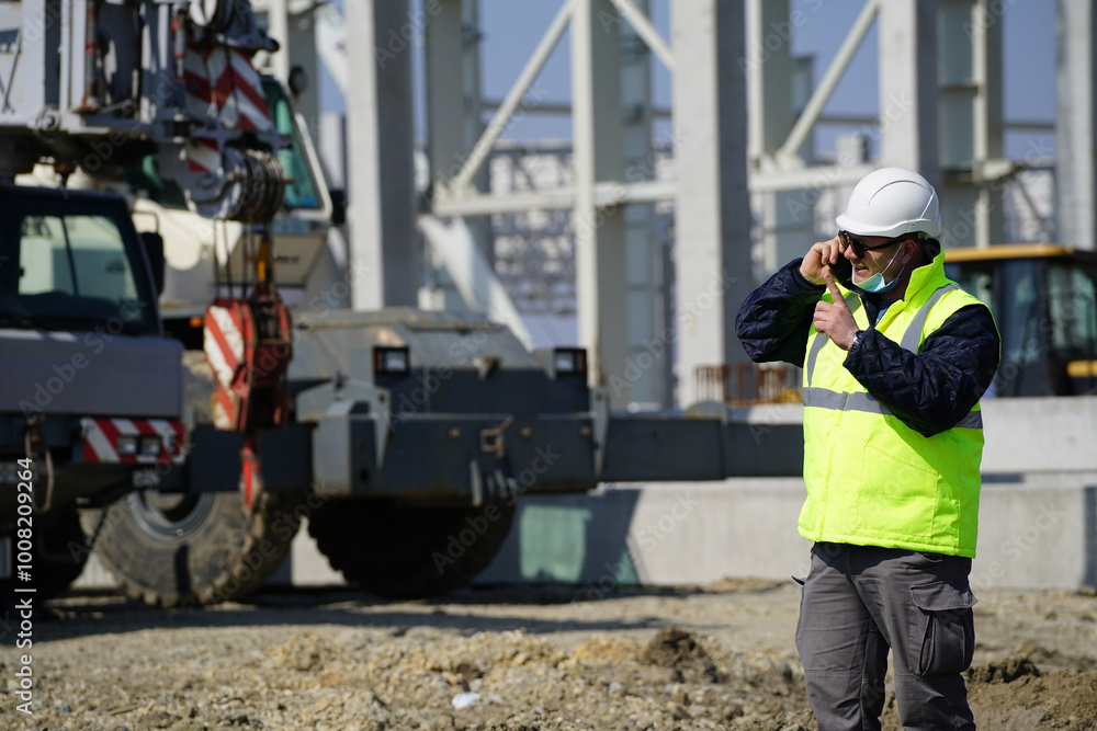 Portrait of young architect with reflective clothing on construction site and with a mask and excavator on the background Portrait of young architect with reflective clothing on construction site and with a mask and excavator on the background