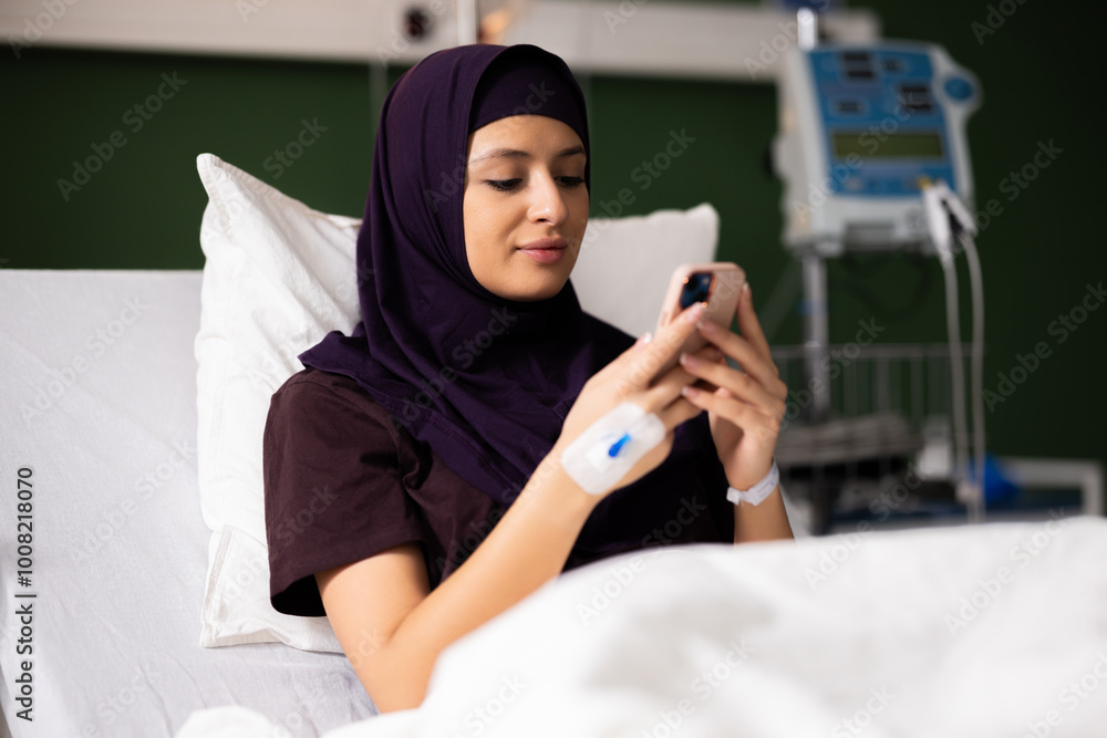 Arab girl in the hospital, connecting with loved ones through her phone, enjoying entertainment, and keeping track of her oxygen levels with an oximeter. Arab girl in the hospital, connecting with loved ones through her phone, enjoying entertainment, and keeping track of her oxygen levels with an oximeter.