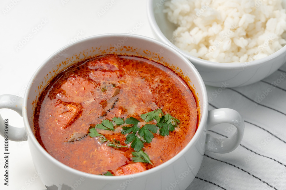 Bowl of curry with pieces of meat and a side of steamed rice arranged neatly for a meal Bowl of curry with pieces of meat and a side of steamed rice arranged neatly for a meal