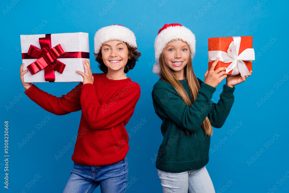 Photo of two kids girl boy smiling hold gift package isolated blue color background Photo of two kids girl boy smiling hold gift package isolated blue color background