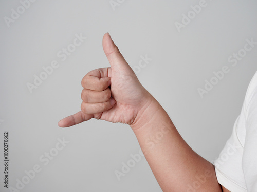 Male person hand shows call me gesture hang loose, over grey