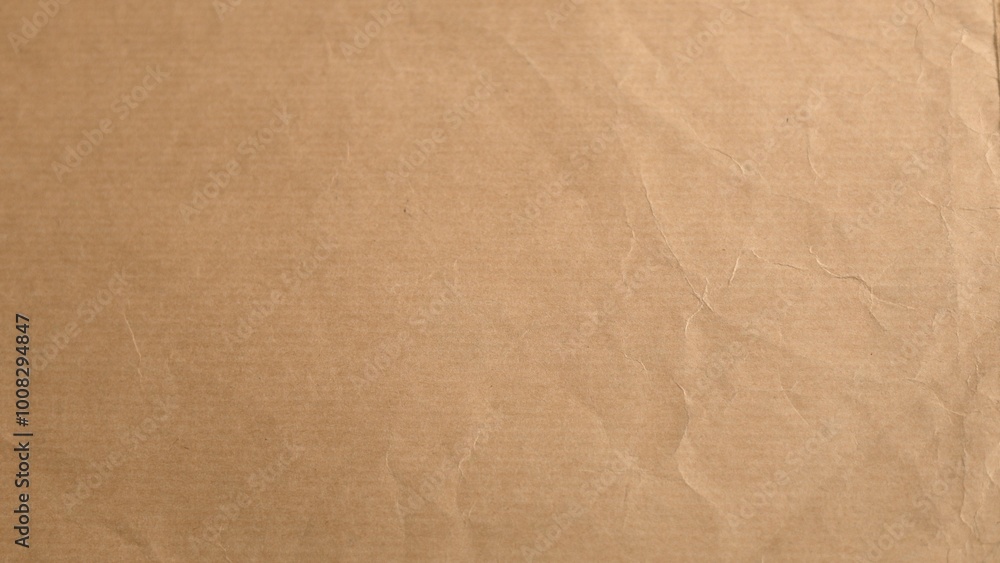 Fototapeta premium Light brown paper displays fine creases forming textured surface. Organic minimal aesthetic highlighted by subtle lighting offering depth to material simplicity