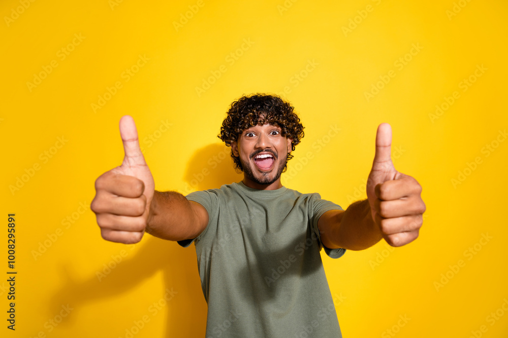 Photo of ecstatic guy with wavy hair dressed t-shirt fingers show you thumbs up approve nice work isolated on yellow color background Photo of ecstatic guy with wavy hair dressed t-shirt fingers show you thumbs up approve nice work isolated on yellow color background