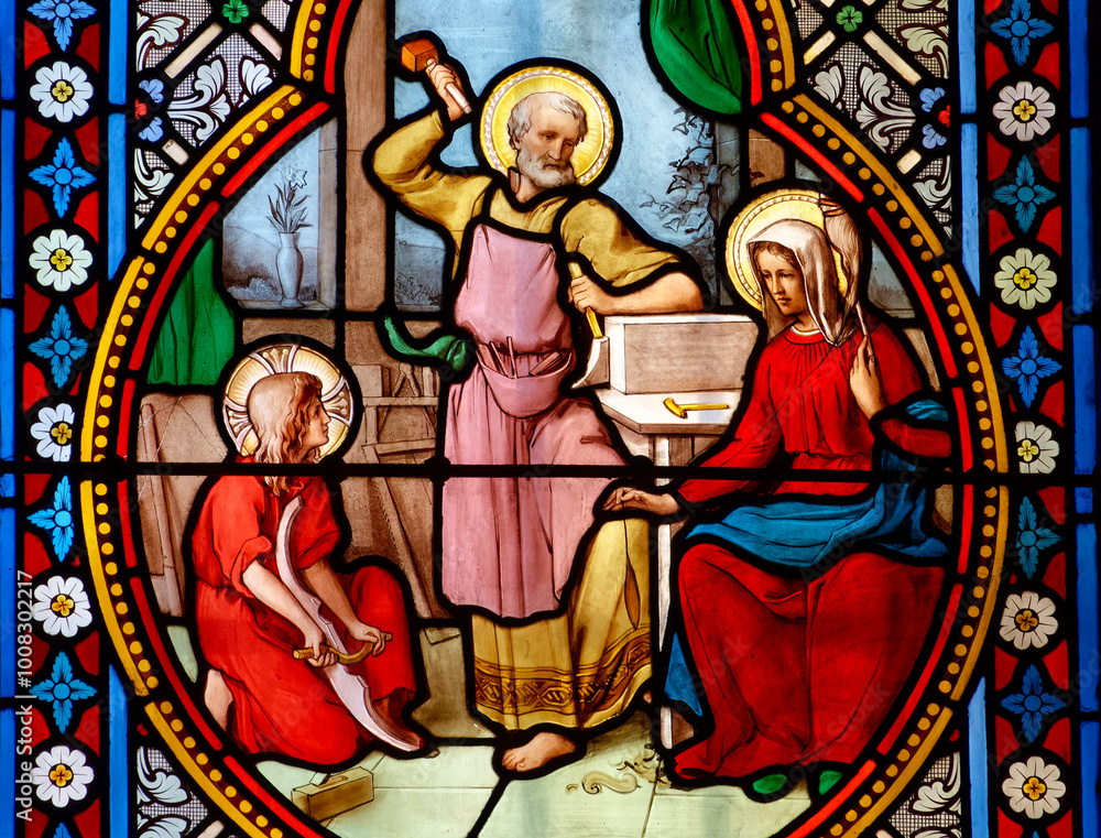Stained glass (19th century) of Holy family: Jesus infant, Virgin Mary and St Joseph in the workshop of Joseph the carpenter. . Stained glass (19th century) of Holy family: Jesus infant, Virgin Mary and St Joseph in the workshop of Joseph the carpenter. .