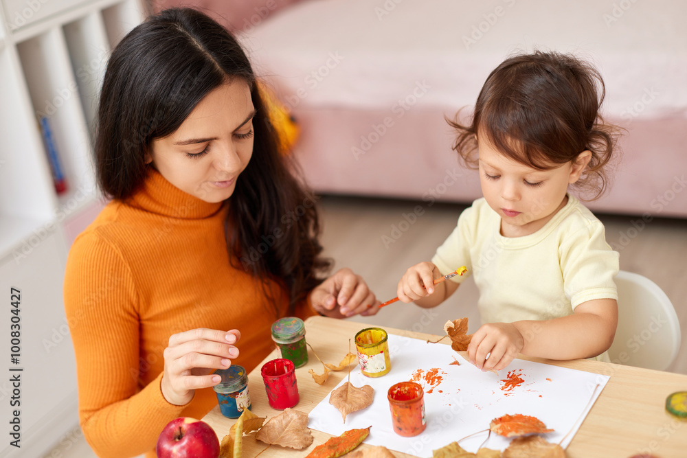happy little child girl and her mother drawing for the autumn holiday. Happy family making autumn decorations together happy little child girl and her mother drawing for the autumn holiday. Happy family making autumn decorations together
