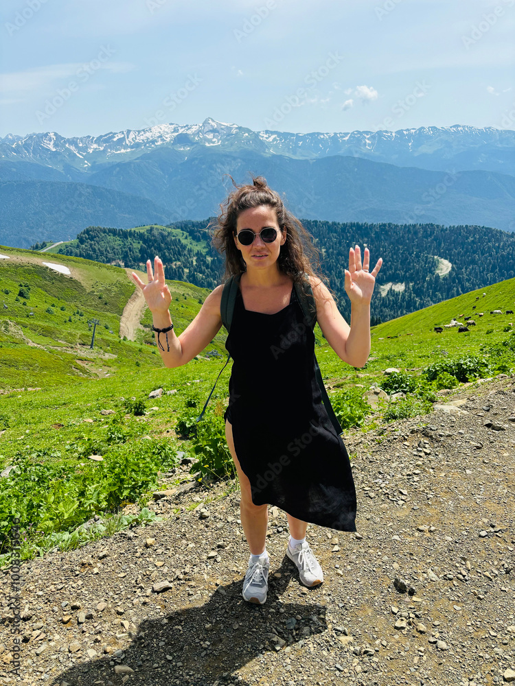 Naklejka premium A tourist girl in a black dress in the mountains