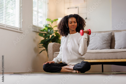 Free Download A curly African American woman in activewear practices yoga in a serene living room Meditating at Home with Headphones setting.
 - GFXLoad