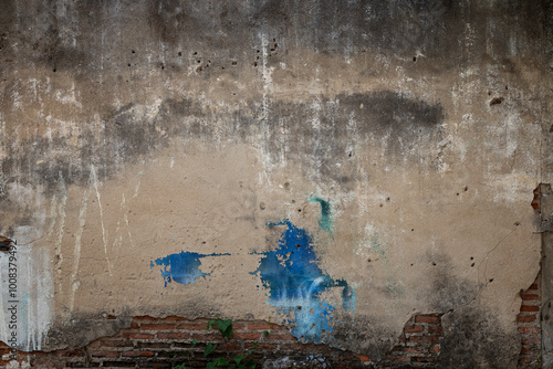 Front view of an old, dirty, damaged and plastered wall. Plaster is partly peeled off revealing old bricks. High resolution full frame textured background.