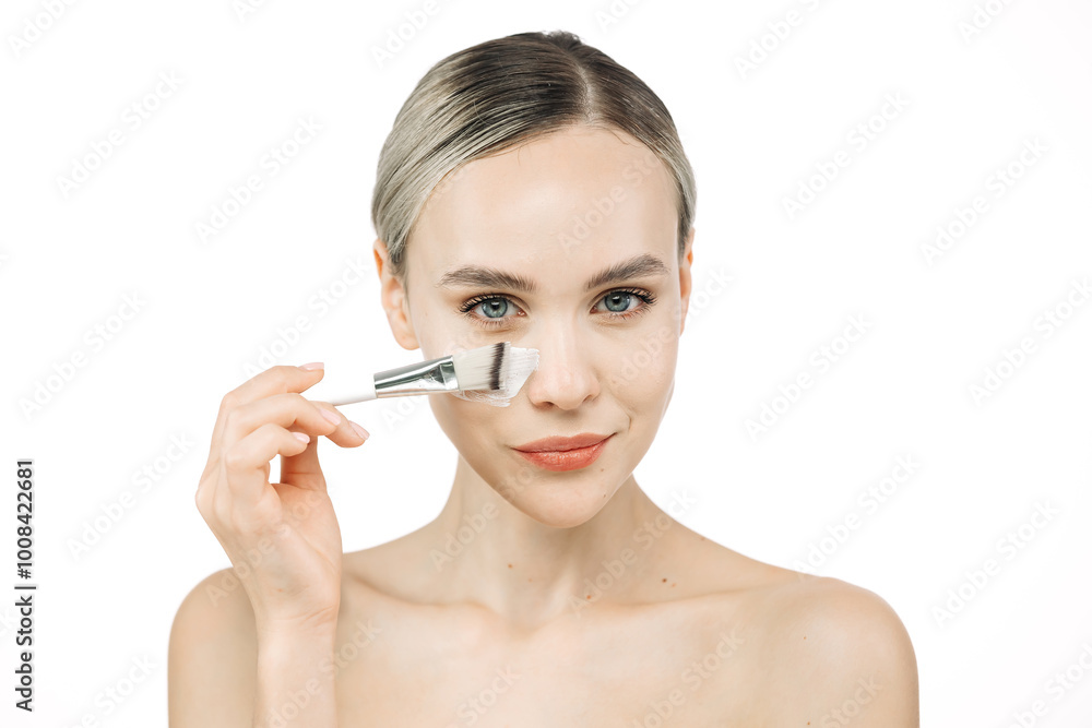 A young woman gently applies cream to her face with a brush. This tender touch emphasizes the importance of skincare and self-care, creating an atmosphere of relaxation and harmony. A young woman gently applies cream to her face with a brush. This tender touch emphasizes the importance of skincare and self-care, creating an atmosphere of relaxation and harmony.