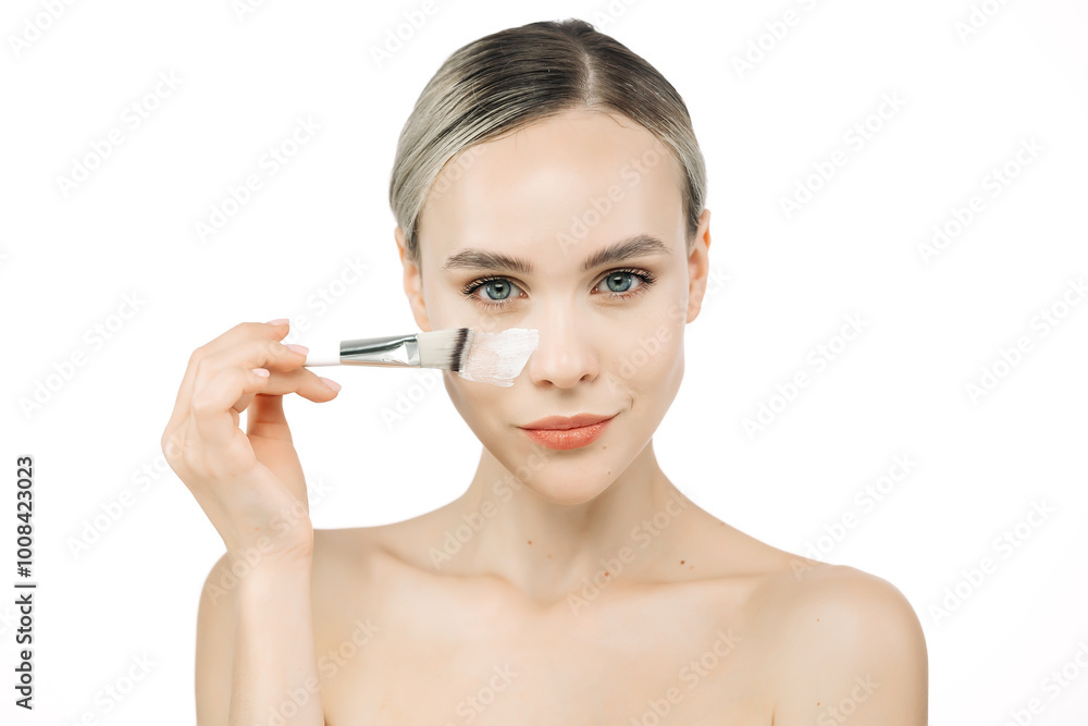 A beautiful woman applies face cream, ensuring perfect hydration for her healthy, fresh skin. This close-up emphasizes the importance of skincare against a white background. A beautiful woman applies face cream, ensuring perfect hydration for her healthy, fresh skin. This close-up emphasizes the importance of skincare against a white background.