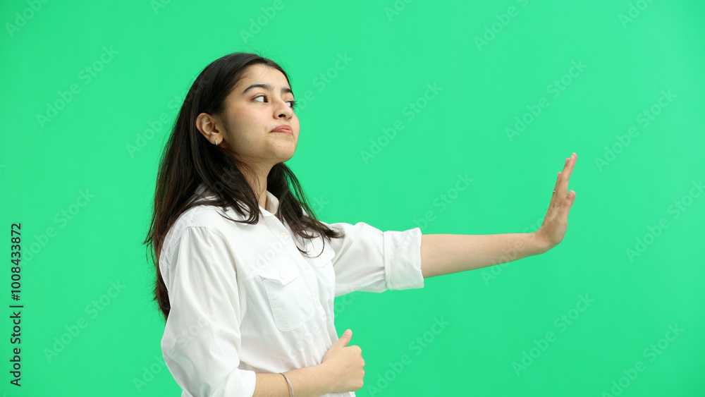 A woman, close-up, on a green background, shows a stop sign A woman, close-up, on a green background, shows a stop sign