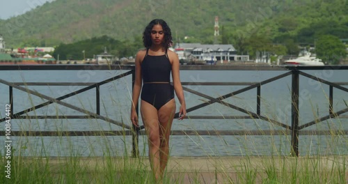 A young girl enjoys the peaceful atmosphere of the boardwalk and beach, dressed in a bikini on a Caribbean island. photo