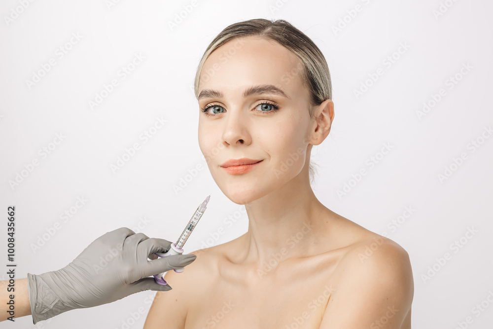 A young beautiful woman receives beauty injections against a white studio background. The close-up highlights the significance of aesthetic cosmetology and injections in maintaining youth and radiance A young beautiful woman receives beauty injections against a white studio background. The close-up highlights the significance of aesthetic cosmetology and injections in maintaining youth and radiance