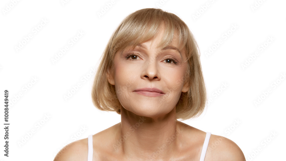 Portrait of beautiful middle aged woman with natural make-up looks at camera calmly against white studio background. Copy space. Concept of beauty, wellness, cosmetology, anti-aging products. Ad Portrait of beautiful middle aged woman with natural make-up looks at camera calmly against white studio background. Copy space. Concept of beauty, wellness, cosmetology, anti-aging products. Ad