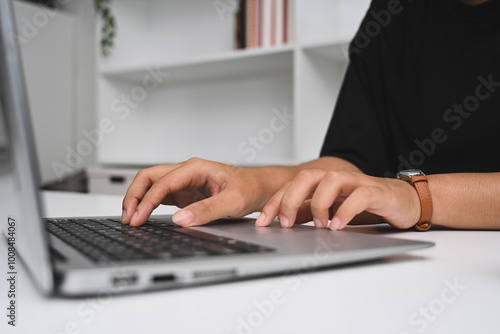 Close- up of hands typing on a laptop keyboard, working on the desk in home office