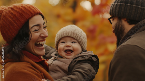 A mother laughing with her baby while the father watches, set against a backdrop of colorful autumn leaves