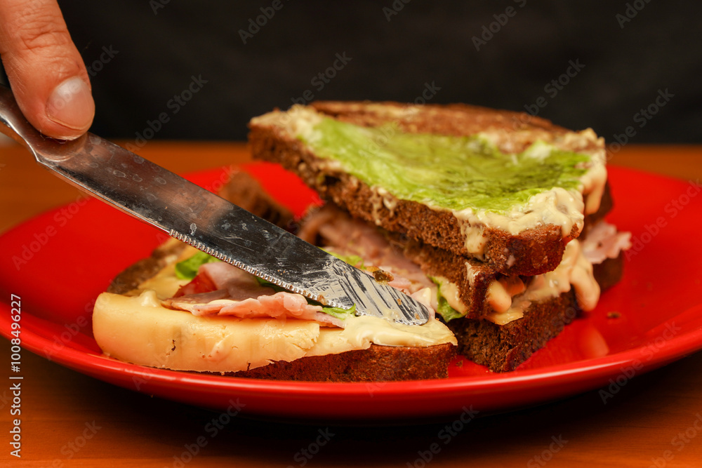 Hands holding sandwich with ham, bacon, cheese, lettuce, tomatoes. Close-up of man eating sandwich. Close-up image of a male cooking and holding sandwich. Food. Tasty sandwich. Opened sandwich. Hands holding sandwich with ham, bacon, cheese, lettuce, tomatoes. Close-up of man eating sandwich. Close-up image of a male cooking and holding sandwich. Food. Tasty sandwich. Opened sandwich.