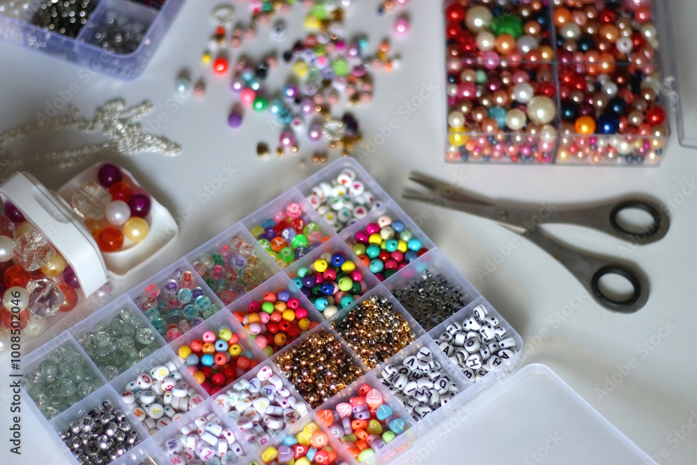 Colorful beads, letter beads, threads and other jewelry making supplies on white background. Making friendship bracelets concept. Selective focus.