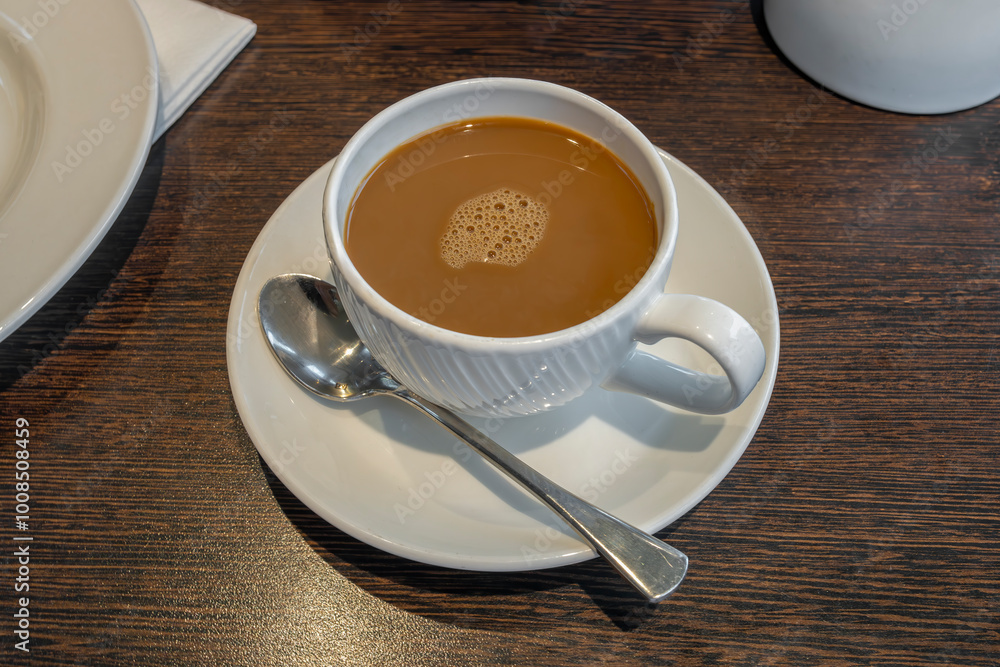Coffee white cup and saucer served with teaspoon on restaurant table Coffee white cup and saucer served with teaspoon on restaurant table