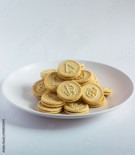 round cookies with various designs on them, including Christmas themed symbols like trees, snowmen, and other festive characters. vanilla or butter flavored sandwich cookies.