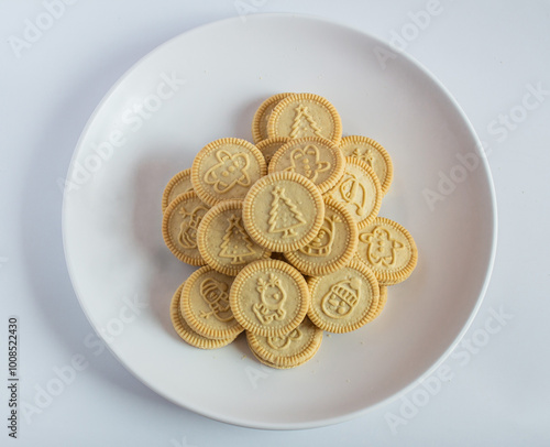 round cookies with various designs on them, including Christmas themed symbols like trees, snowmen, and other festive characters. vanilla or butter flavored sandwich cookies.
